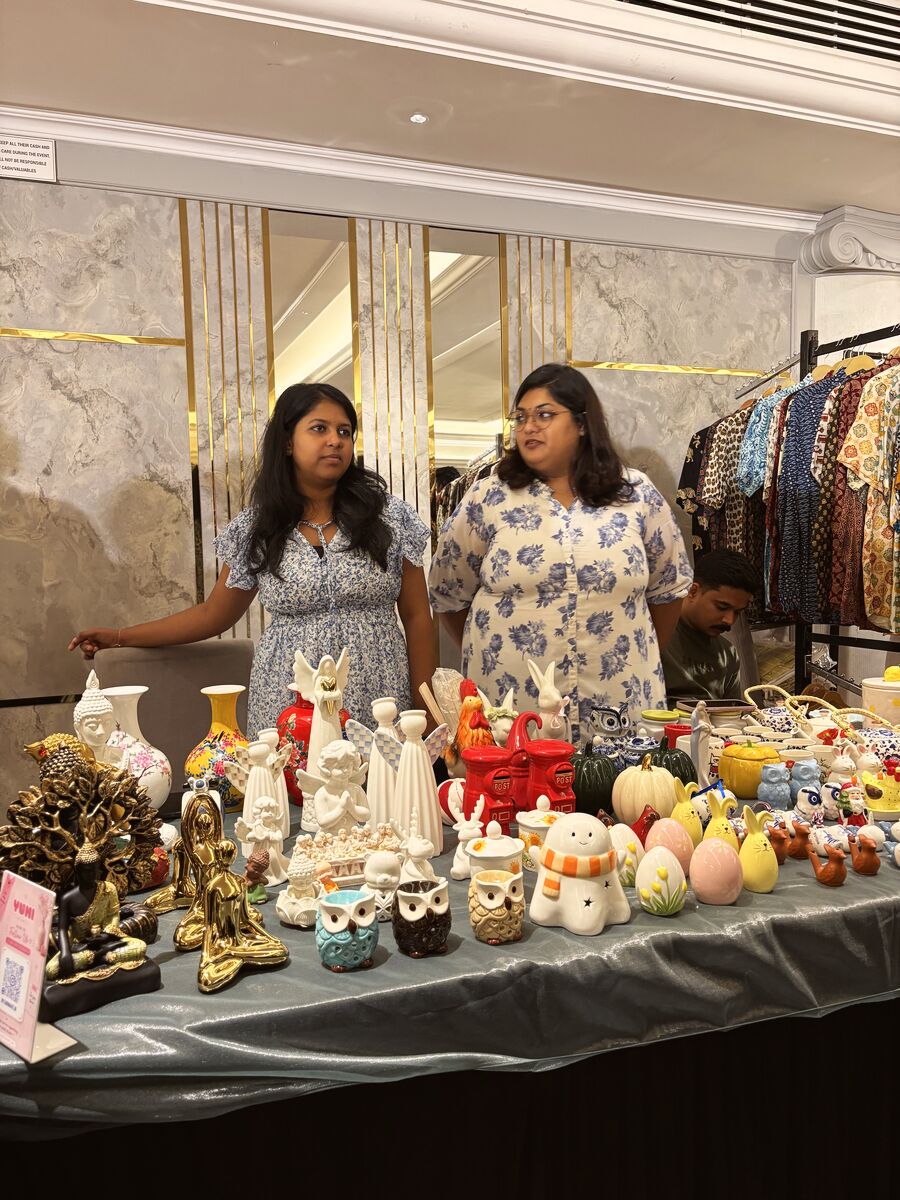 Two vendors at a stall of ceramic figurines and decor